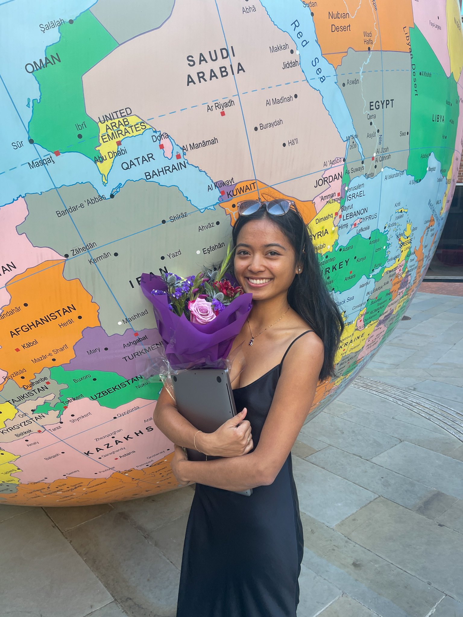a student studying abroad in London standing in front of a giant globe