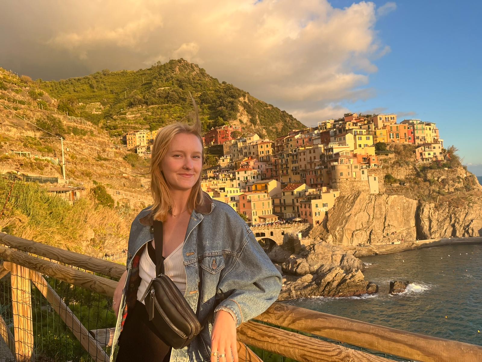 a student studying abroad in France posing in front of a bunch of colorful houses on the cliff above the ocean