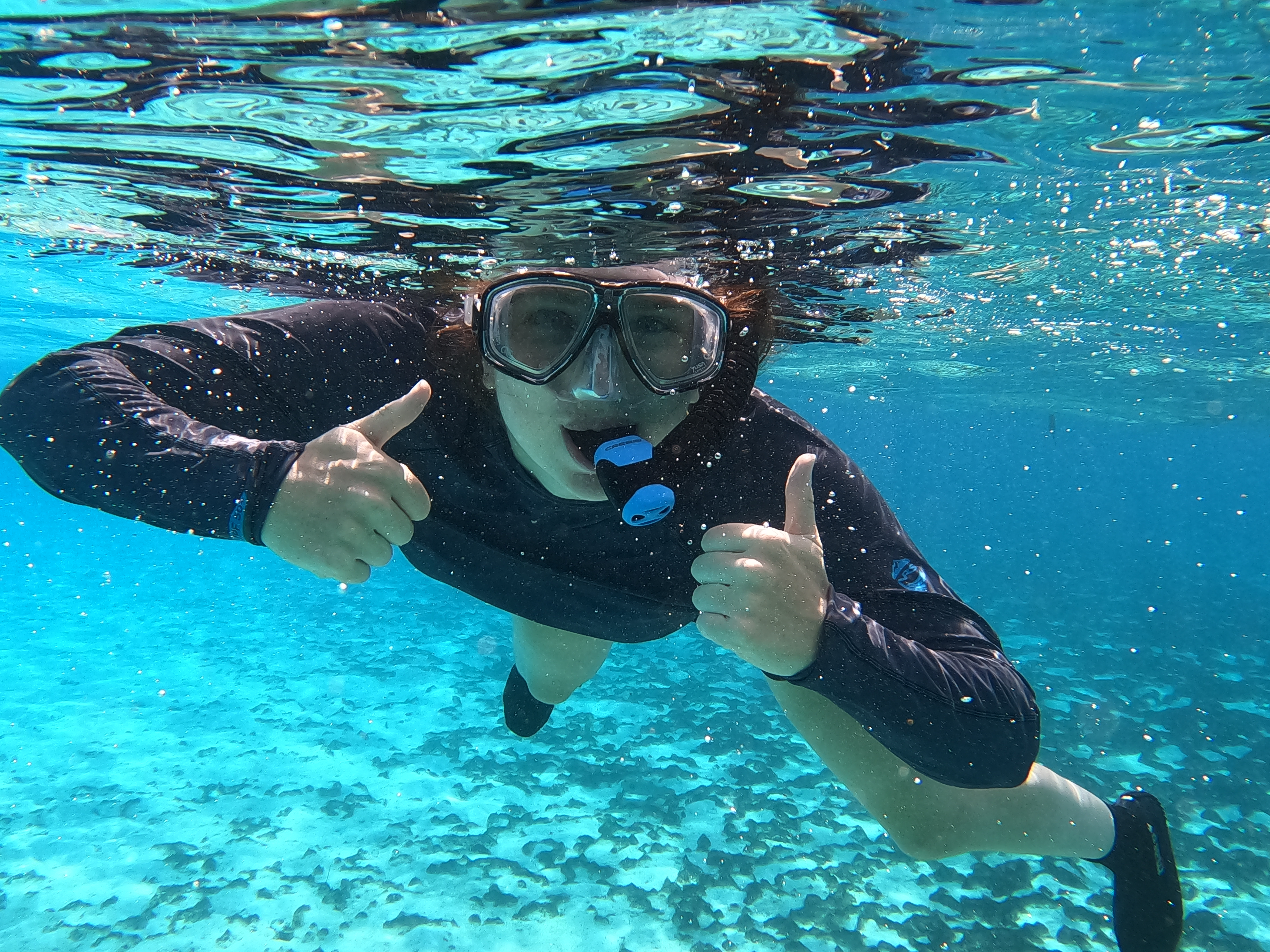 A student studying abroad in French Polynesia wearing a snorkel underwater