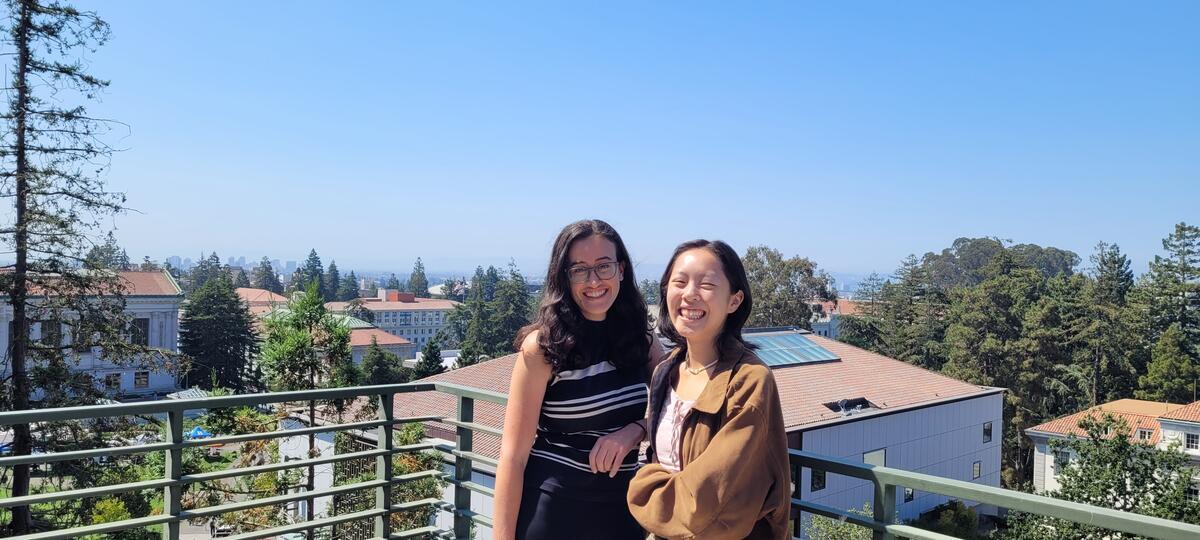 BUGs Co-Presidents, Fiona & Annabelle, smiling at the camera standing on a balcony overlooking Cal