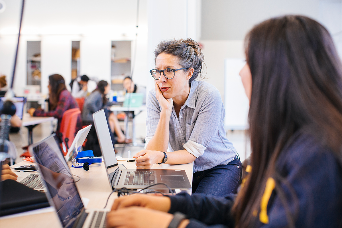Professor speaking with student on laptop