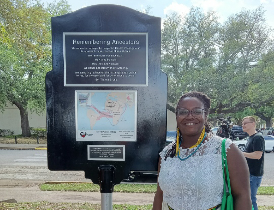 Tianna Bruno stands next to a marker dedicated to enslaved peoples brought to Texas by sea